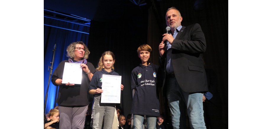 Bürgermeister Jörg Schmidt, Schulleiterin Elke Weyers mit zwei Kindern zeigen die Urkunden