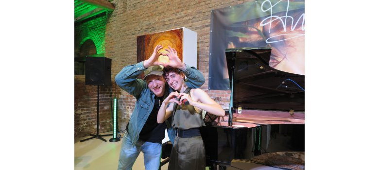 Lachende Anny Ogrezeanu und Jens Gilles formen ihre Hände zu Herzen. 